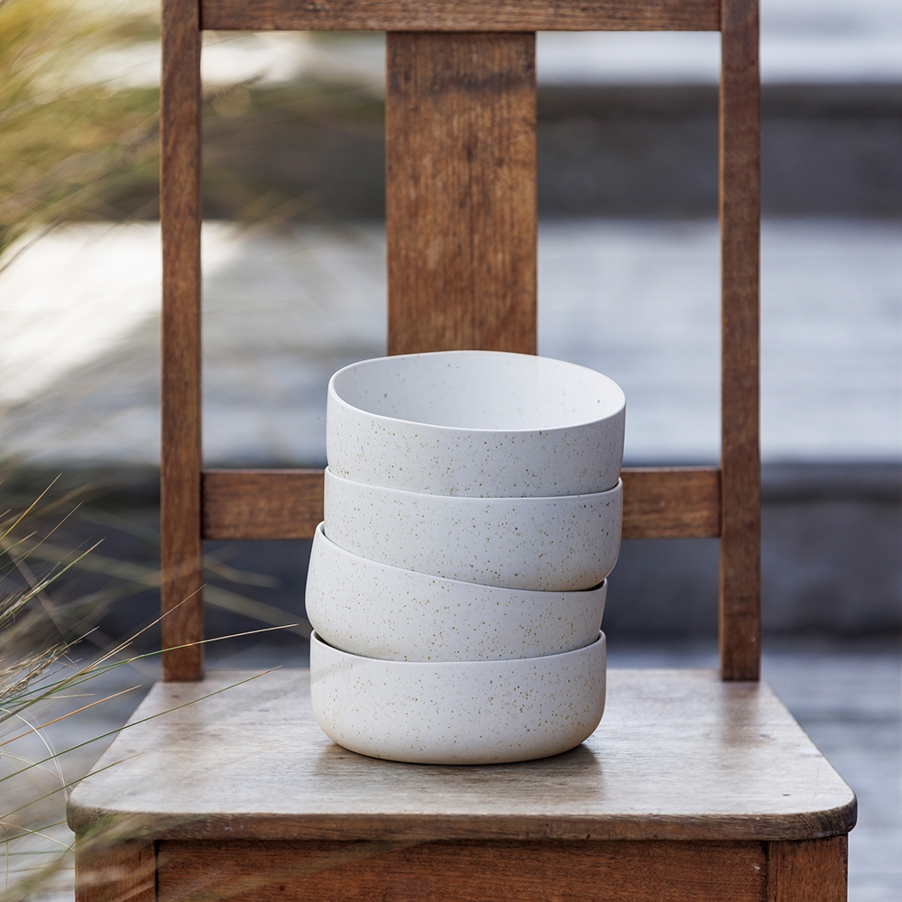 Ecology Domus recycled stoneware bowls stacked in 4 on a wooden chair.